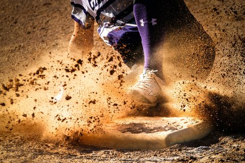 A runner sliding into base, dirt flying