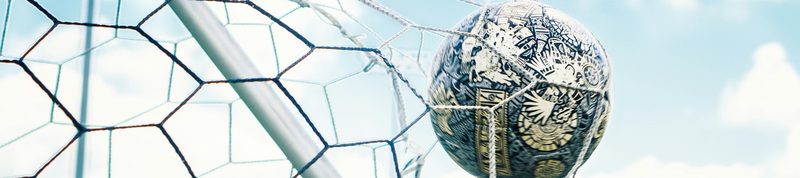 A soccer ball hitting the back of the net against a blue sky